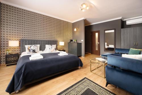 a bedroom with a large bed and a blue couch at Wine & Wellness hotel Besední dům in Valtice