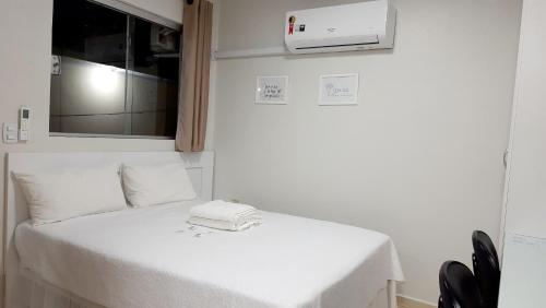 Cama blanca en habitación con microondas en Flat 01, en Jaguariaíva