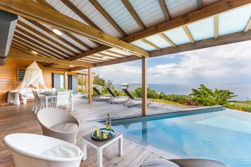 un patio extérieur avec une piscine, des tables et des chaises dans l'établissement Calypso Bay, à Bouillante