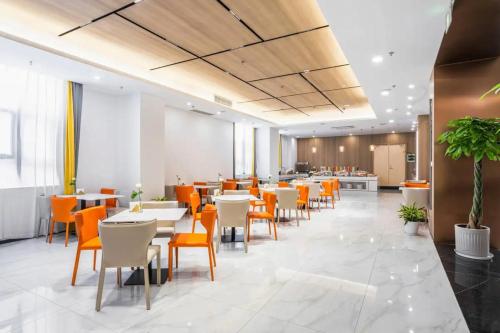 a restaurant with white tables and orange chairs at Veegle By Landison Ningbo in Ningbo