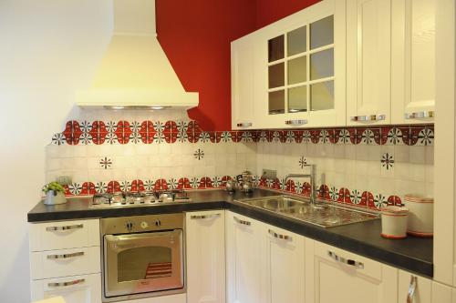 a kitchen with white cabinets and red and white tiles at B&B La Teiera in Boario Terme