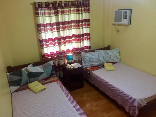 a room with two beds and a window at TGH Guest House Badian in Badian