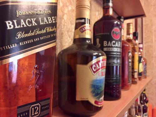a shelf with several bottles of alcohol on it at TGH Guest House Badian in Badian
