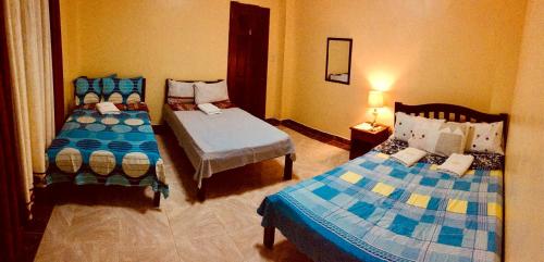 a bedroom with two beds and a lamp in it at TGH Guest House Badian in Badian