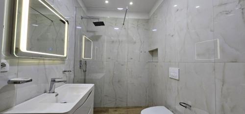 ein weißes Badezimmer mit einem Waschbecken und einem Spiegel in der Unterkunft TAM 2BDR Centre Apartment With Veranda in Tirana