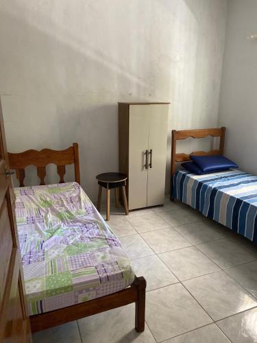 a bedroom with two beds and a cabinet and a table at Beleza e praticidade no bairro Mirante in Santa Cruz Cabrália