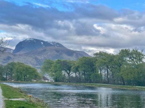 a mountain in the distance with a river and trees at Station Cottage in Fort William