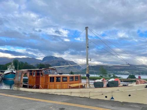 a boat is docked in the water next to a road at Station Cottage in Fort William