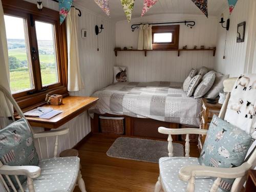 a small bedroom with a bed and a desk and chairs at Shepherd's Hut Bilsdale in Chop Gate