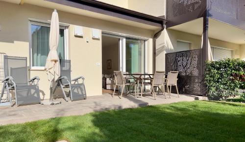 a patio with a table and chairs and an umbrella at Hotel Gartenresidence Zea Curtis in Merano