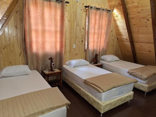 three beds in a room with wooden walls at Fi-Scheer Bungalows in Bella Vista