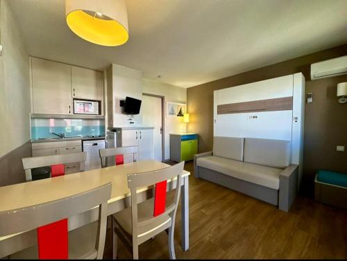 een keuken met een tafel en stoelen en een bank bij Mandelieu / Appartement Climatisé 4 prsn / Piscine in Mandelieu-la-Napoule