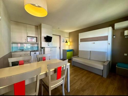 une cuisine avec une table, des chaises et un canapé dans l'établissement Mandelieu / Appartement Climatisé 4 prsn / Piscine, à Mandelieu-la-Napoule