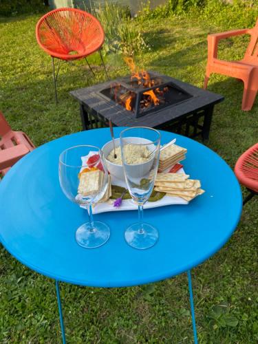 une table bleue avec deux verres et une assiette de nourriture dans l'établissement Maison Zen et Jacuzzi proche des passerelles himalayennes de Monteynard, à Vif