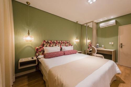 a bedroom with a large white bed with green walls at Araçatuba Plaza Hotel in Araçatuba