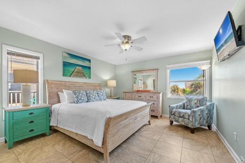a bedroom with a bed and a chair and windows at Villas on the Gulf Unit D2 in Pensacola Beach