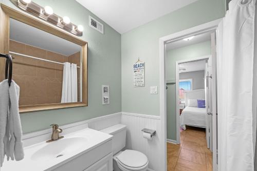 a bathroom with a sink and a toilet and a mirror at Villas on the Gulf Unit D2 in Pensacola Beach