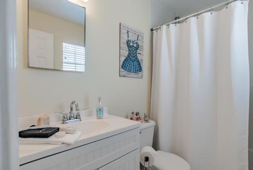 a white bathroom with a sink and a shower curtain at Stylish Condo with a view of the water in Dauphin Island