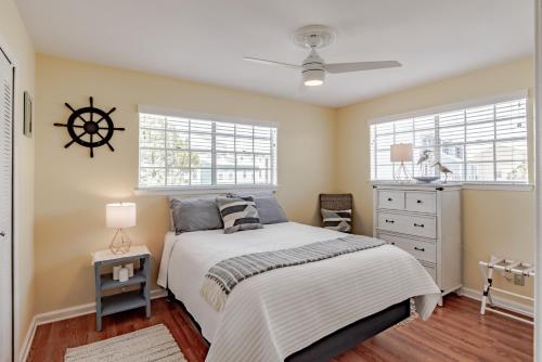 a bedroom with a bed with a dresser and two windows at Stylish Condo with a view of the water in Dauphin Island