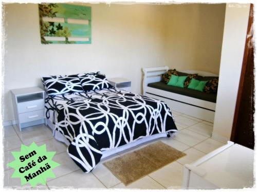 1 dormitorio con 1 cama con edredón blanco y negro en Suítes de Setiba - HOSPEDARIA OCA RUCA, en Guarapari