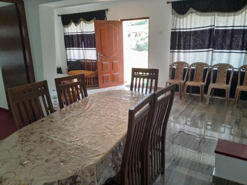 comedor con mesa, sillas y puerta en Harrisline Holiday Homes, en Nuwara Eliya
