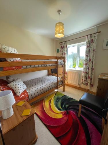 a room with two bunk beds and a rug at Honeycomb Cottage - a quiet, charming, cosy retreat in the countryside only 2 miles from one of Cornwall's best beaches in Truro