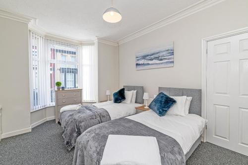 two beds in a room with two windows at Scott House - Contractor Friendly - Sleeps 7 in Liverpool