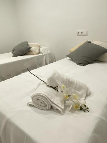 Una cama blanca con una toalla y flores. en El Velero una terraza al mar, en Calafell