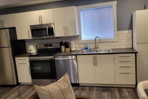 una cucina con armadi bianchi e un apparecchio in acciaio inossidabile di Beautiful newly designed Luxurious Apartment a Windsor