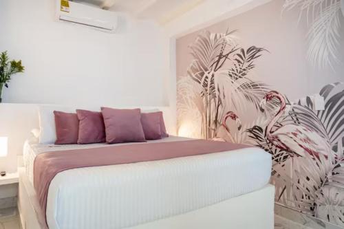 ein Schlafzimmer mit einem Bett mit lila Kissen und einem Wandbild in der Unterkunft Casa Verde Hotel in Santa Marta