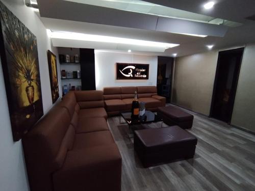 ein Wohnzimmer mit einem braunen Sofa und einem Tisch in der Unterkunft Aparta-Suites Mirador del Recuerdo in Bogotá