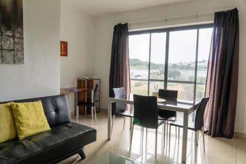 uma sala de estar com um sofá, uma mesa e uma janela em Cozy Bedroom, shared bathroom -Gzira em Il-Gżira