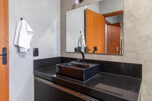La salle de bains est pourvue d'un lavabo noir et d'un miroir. dans l'établissement Casa recém construída no Campeche Central HA6831, à Florianópolis