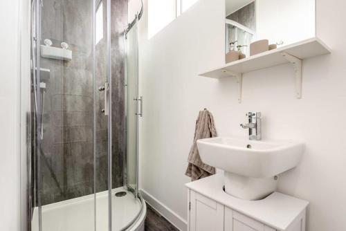 a white bathroom with a sink and a shower at Cosy 1 Bedroom Apartment in Central Sheffield in Sheffield