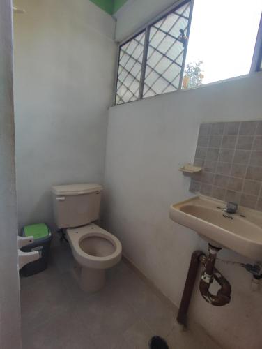 a bathroom with a toilet and a sink and a window at Hostal Xiinbal Valladolid in Valladolid