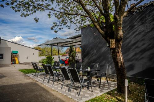 a table with chairs and an umbrella next to a tree at Plaza La - Night and Spa in Sremska Mitrovica