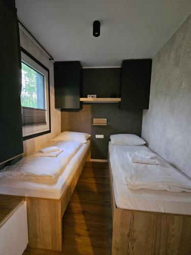 two beds in a small room with a window at Mobilna hiška pod Lipo in Velenje