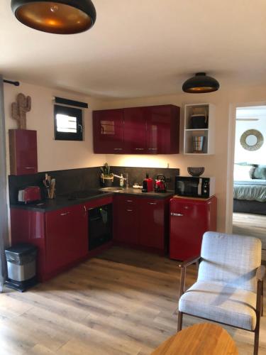 - une cuisine avec des placards rouges et une chaise blanche dans l'établissement Appartement Rez de Jardin, à Cavalaire-sur-Mer