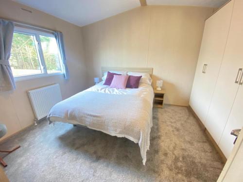 a bedroom with a large white bed with pink pillows at Caravan in morecombe in Morecambe