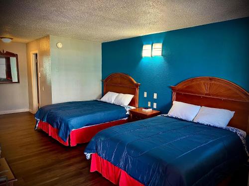 a hotel room with two beds and a blue wall at Hotel Regency Inn in San Antonio