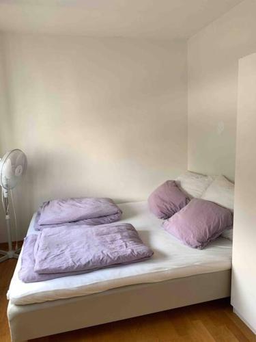 a bed with purple pillows on it in a room at Leilighet i hjertet av kristiansand sentrum! in Kristiansand