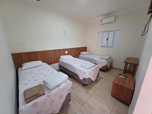 a room with three beds and a table and a window at HOTEL TABARANA in Ubarana
