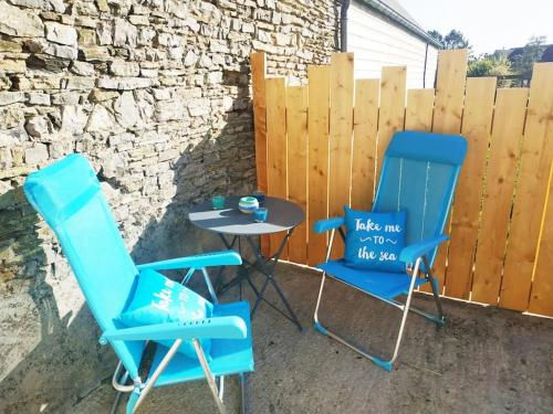 two blue chairs and a table on a patio at Le gîte du havre in Portbail