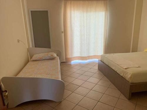un dormitorio con dos camas y una ventana en Dine Apartment, en Sarandë