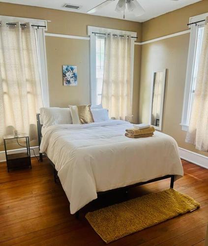 a bedroom with a large bed with white sheets and windows at Historical Hideaway at Jacksonville in Jacksonville