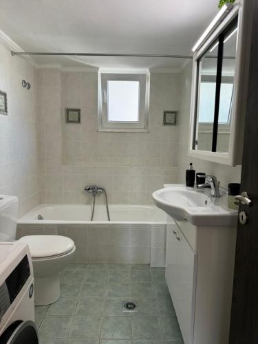 La salle de bains est pourvue d'une baignoire, de toilettes et d'un lavabo. dans l'établissement Navaro Apartments, à Patras