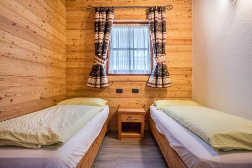 Habitación de madera con 2 camas y ventana en Trilocale Chalet Camping Faè 6, en Madonna di Campiglio