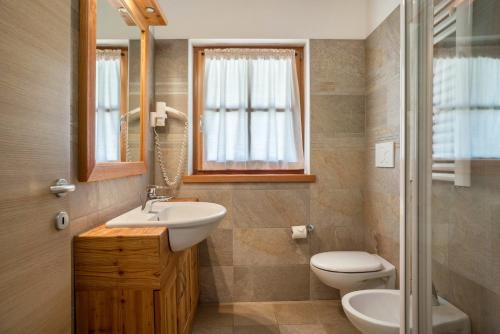 y baño con lavabo, aseo y espejo. en Trilocale Chalet Camping Faè 6, en Madonna di Campiglio