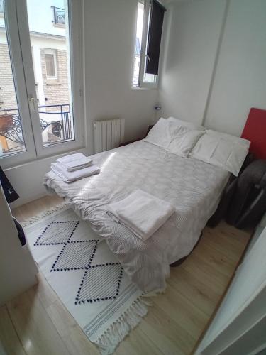 une chambre avec un lit avec des draps blancs et une fenêtre dans l'établissement Paris 11 Studio, à Paris