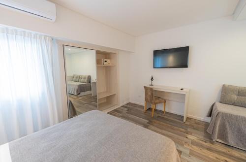 a bedroom with two beds and a desk and a mirror at Sennac Hotel in Mar del Plata